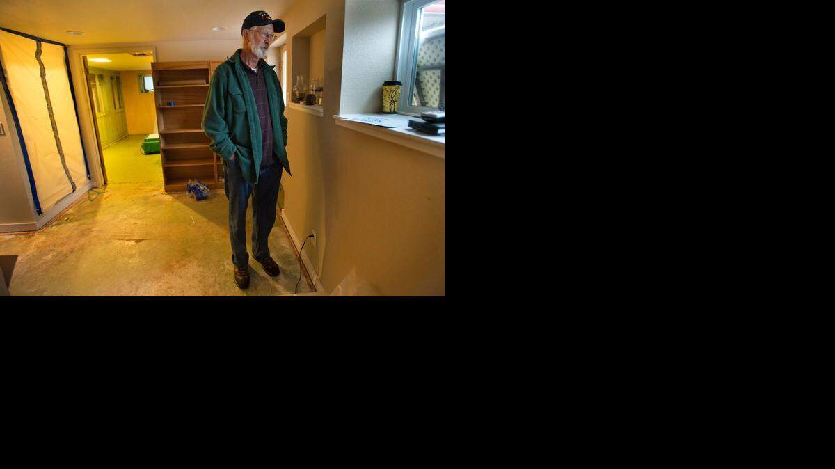 
Steve Larson peers out a window in his damaged Auburn home on Thursday, three weeks after a man accused of killing two law-enforcement officers fled there before authorities forced his surrender by laying siege to the house with tear-gas canisters. 
