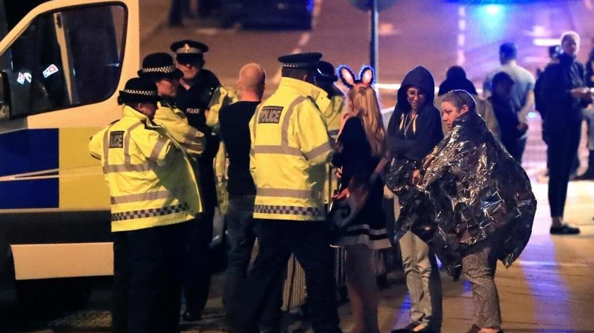 Emergency services personnel speak to people outside Manchester Arena on Monday after reports of an explosion at the venue during an Ariana Grande concert in Manchester, England.