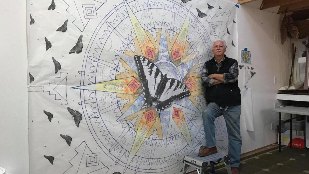 Stan Padilla stands next to a mock-up of the “Flight” mural scheduled to be unveiled on March 1.