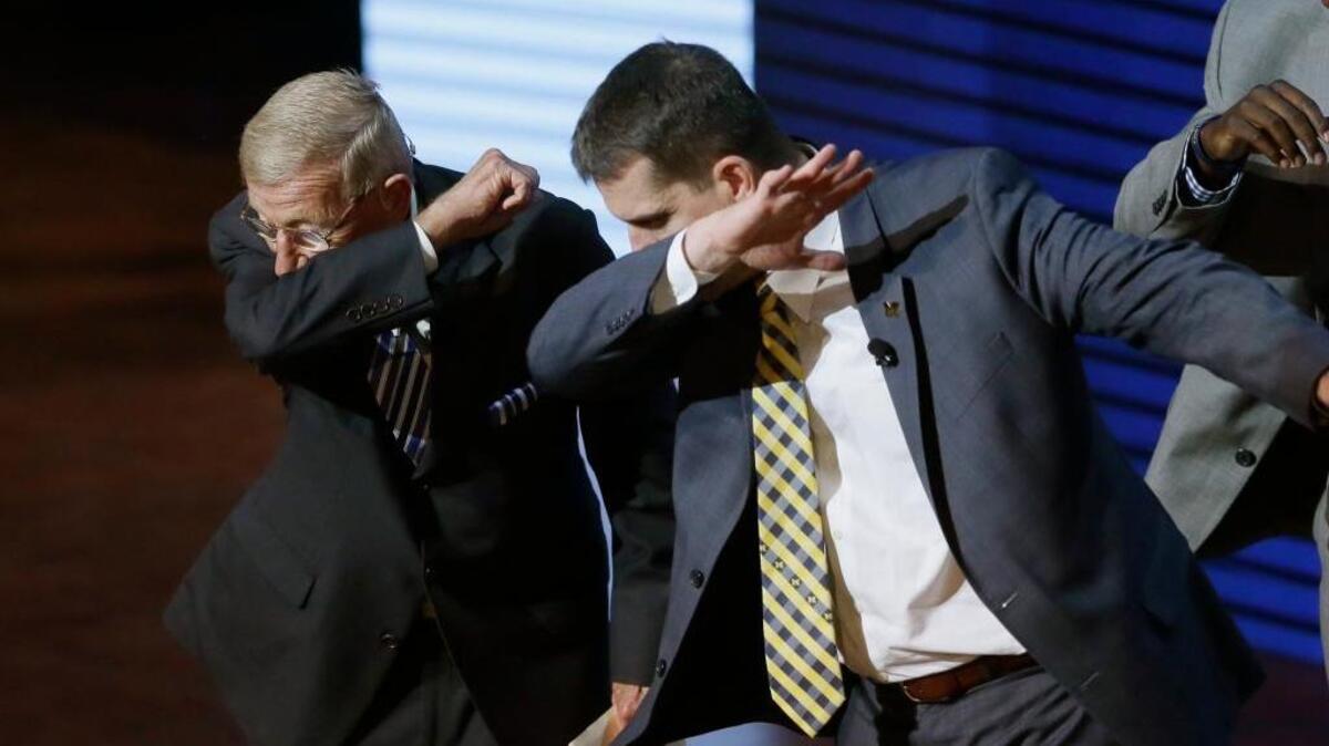 Former college football coach Lou Holtz, left, and Michigan coach Jim Harbaugh perform a dab in 2016. Nintendo said that “Dabbing is E for everyone” Wednesday on Twitter. Most followers took issue with the tweet.