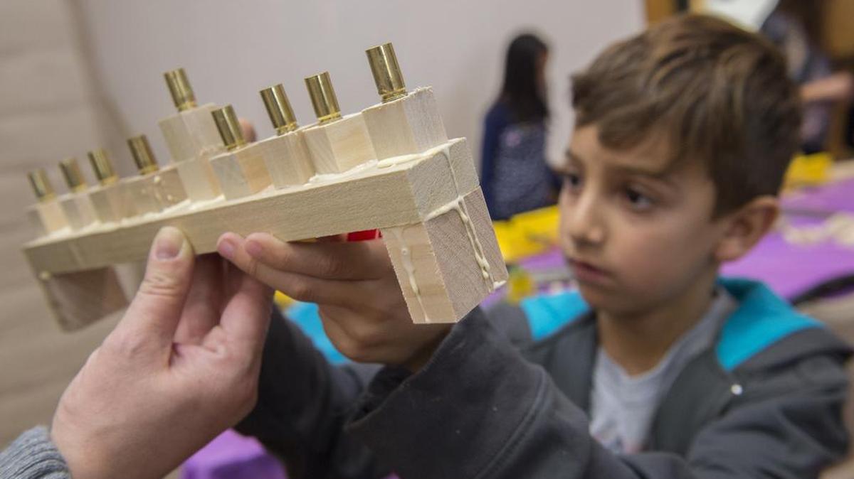 Aiden Rashidi, 8, of Folsom signs a Menorah he made out of bullet shells and wood along with other children during a workshop on Sunday, Dec. 6, 2015, at Folsom Community Center.