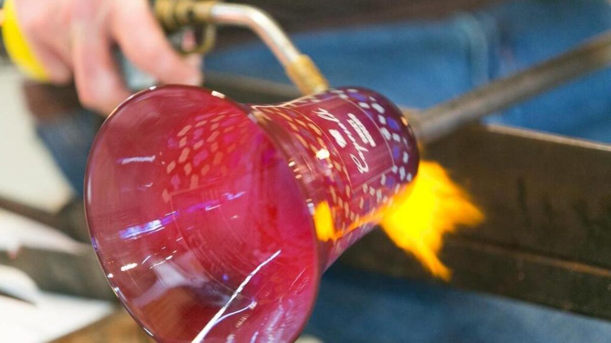 A blow torch puts the final touches on a glass vase.