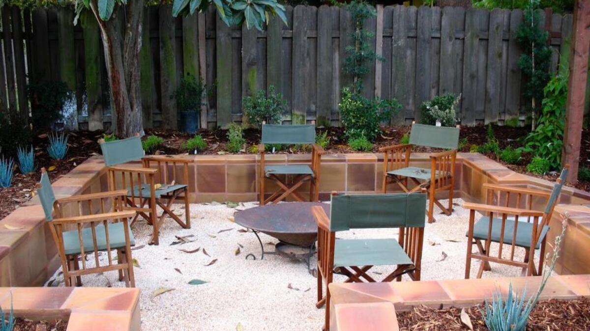 Tiled walls made with tiles from Gladding McBean in Lincoln surround a sitting area filled with Sonoma gold crushed gravel in this landscape design.