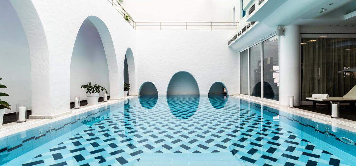 Sunlit indoor pool at Aegialis Hotel & Spa on the cliffs of Amorgos, Greece.