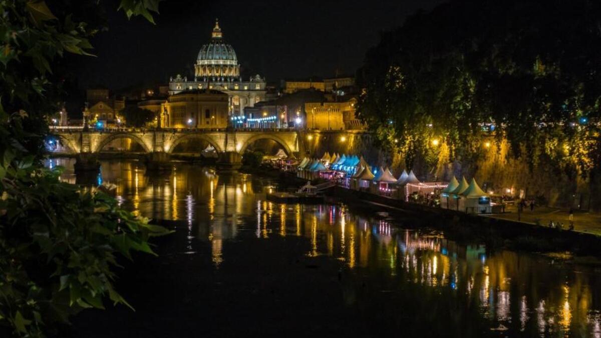 After my recent trip to Rome, I thought other readers might be interested in this photo at a Roman riverfront, considering everyone’s interest in Sacramento’s riverfronts: St. Peter’s Basilica on the Tiber River in Rome. The massive structure, here in the background, is cavernously opulent inside, grandly inspiring outside, and beautiful at night. The vendor and entertainment tents dotted all up and down the river like those pictured in the foreground here come alive long after dark. They have many different types of music at different locations, and the ones here had a terrific Dixieland band.