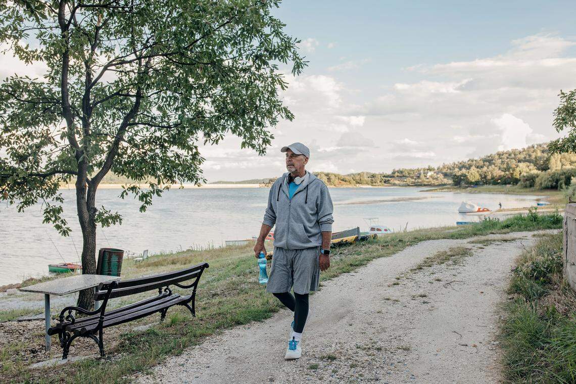 Photo of a senior man walking on a natural jogging path.