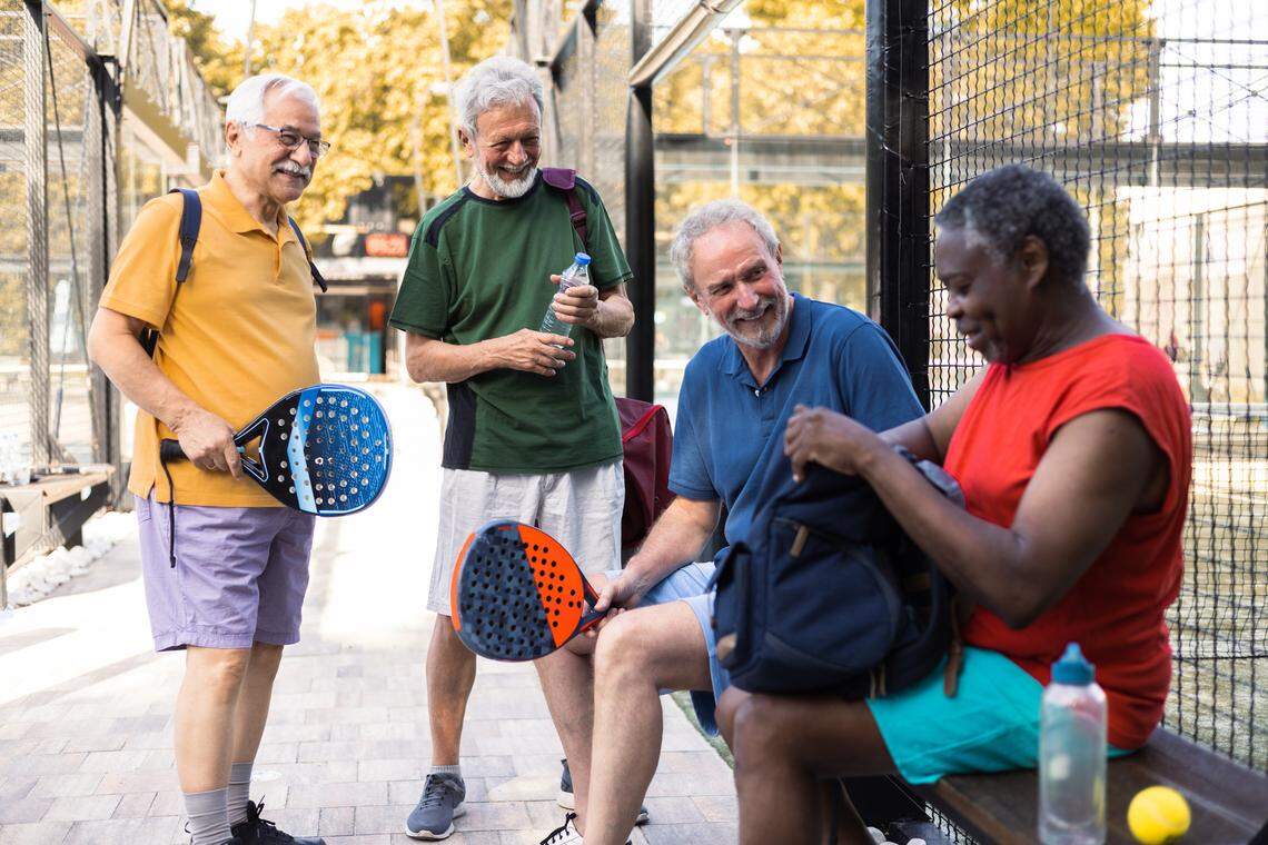 Four senior men meeting for a paddle ball match in doubles.