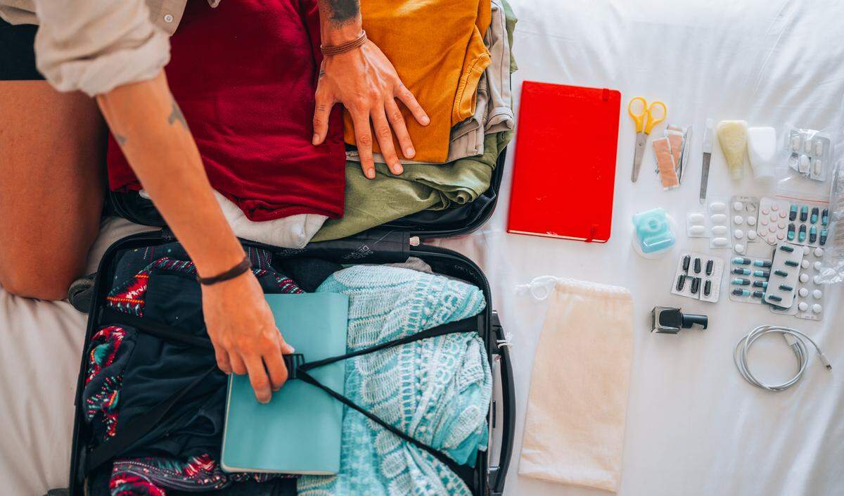 An man packing clothes and all the travel essentials in a suitcase.