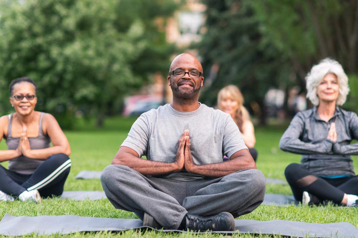 A group of seniors practices yoga outside.
