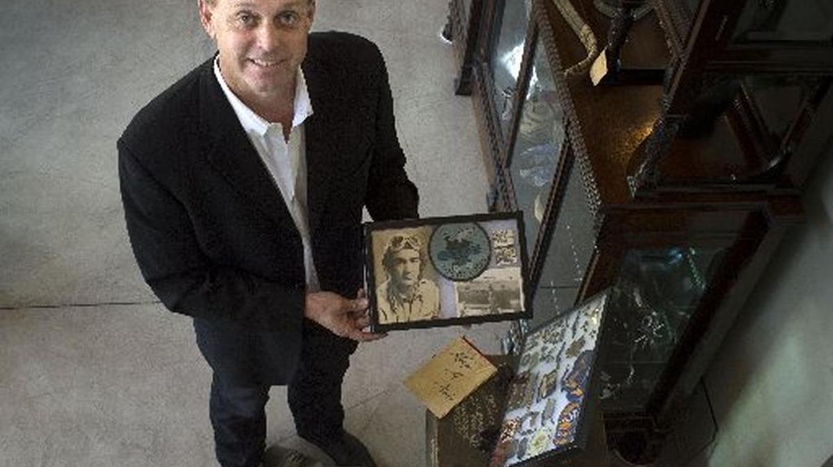 Brian Witherell holds a photo with a patch near other World War II items of the late insurance company founder James O. Burpo that were auctioned by Sacramento-based Witherell’s.