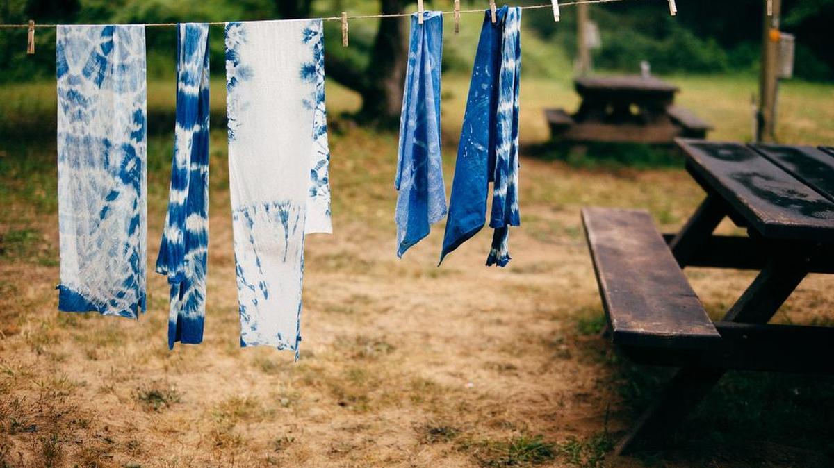 Scarves created with the shibori dyeing technique hang on a clothesline to dry.