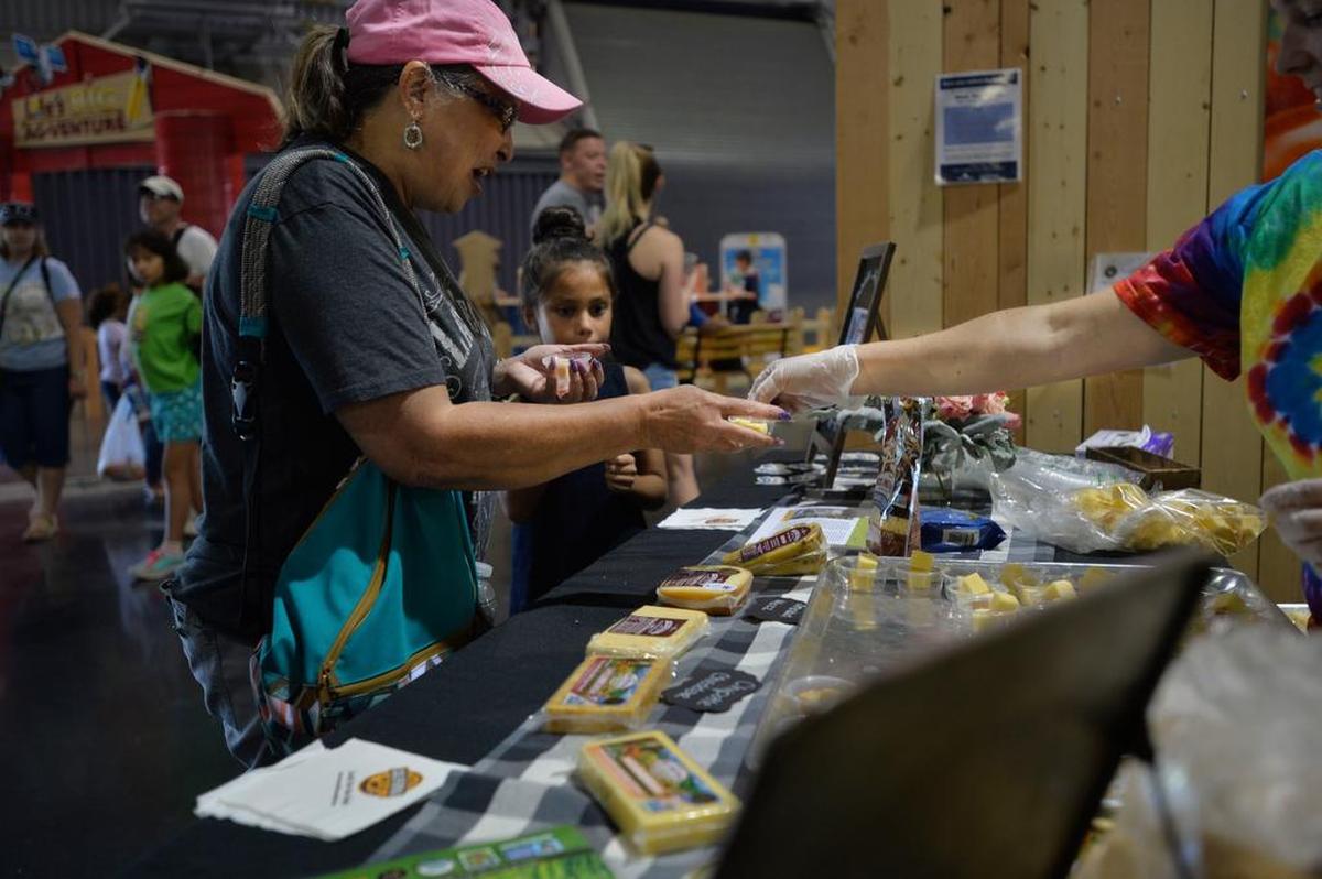 Megan Enyeart hands out locally-produced cheeses for customers to taste at the California State Fair in Sacramento on Tuesday, July 24 2018.