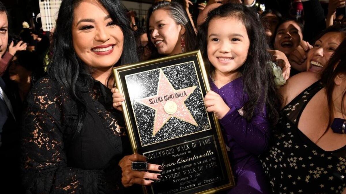 Suzette Quintanilla, left, sister of the late singer Selena Quintanilla, holds a replica of her sister's star on the Hollywood Walk of Fame as she poses with young fan Sammi Corona-Lampa, 4, of Moreno Valley, Calif., following a posthumous star ceremony for Selena on Friday, Nov. 3, 2017, in Los Angeles.