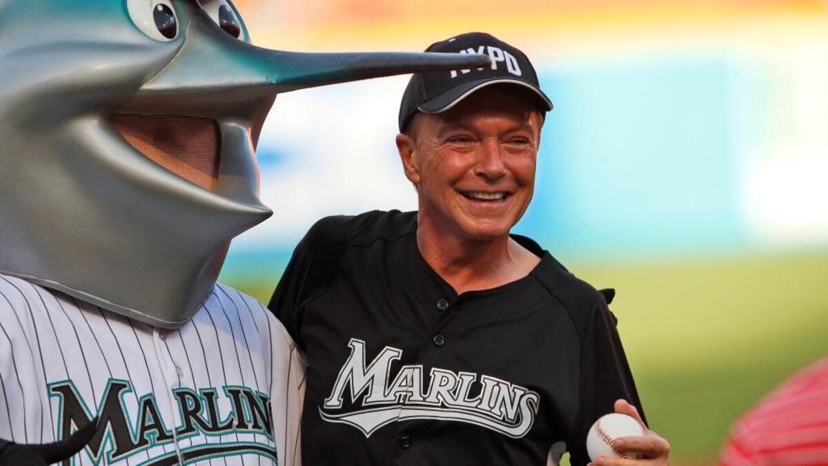 David Cassidy poses with Florida Marlins mascot Billy the Marlin before throwing out the first pitch on July 9, 2011, in Miami. Cassidy died Tuesday at the age of 67.