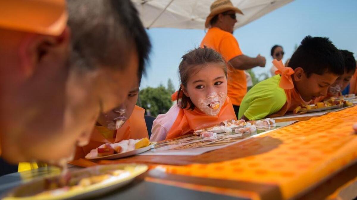 
Miya Nelson, 8, center, watches her competitors during the peach eating contest at BeMoneySmartUSA’s Peach Festival on Saturday in Folsom.
