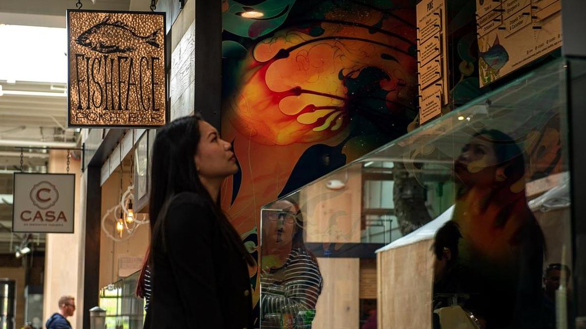 A customer looks at the menu of Fish Face Poke Bar in Emeryville’s Public Market. Owner Billy Ngo founded Fish Face in Sacramento.