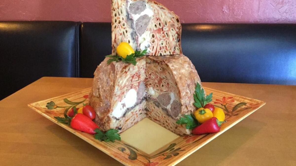 A cut Sampino’s timbale showcases the inside of the pie, filled with penne pasta, meatballs, hard-boiled eggs, salami, fresh mozzarella and provolone.