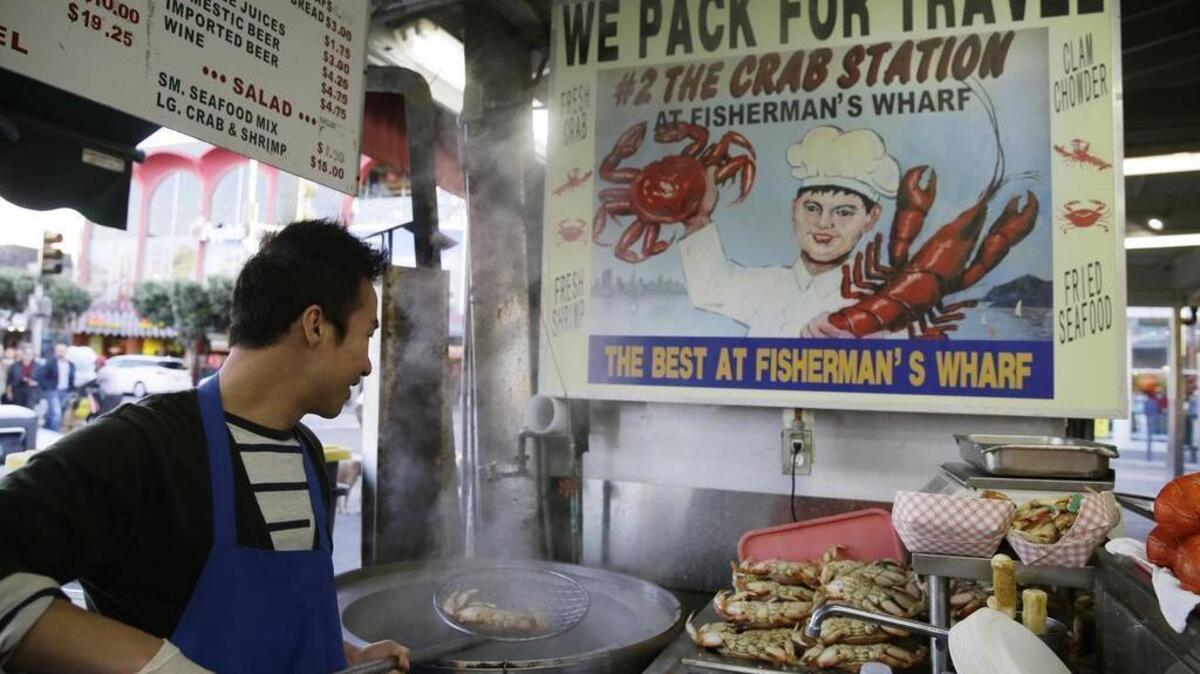 In this photo taken Tuesday, Nov. 10, 2015, Jinsen Zhao pulls an imported Dungeness crab from the Northwest out of a cooker at Fisherman's Wharf in San Francisco.