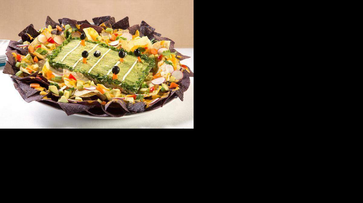 
Guaca-BOWL-e nachos stadium (recipe, Page D2) has mashed avocados for the field, sour cream for the yard lines, olives on carrots for players, and a colorful assortment of edibles for the fans.
