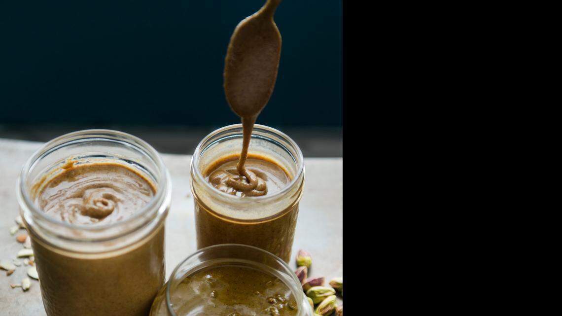 
Cookbook author Garrett McCord stirs jars of nut butters he made late last month at his home. Clockwise from upper left are vanilla spiced almond, salted honey pistachio and maple pecan. See recipes, Page D2.
