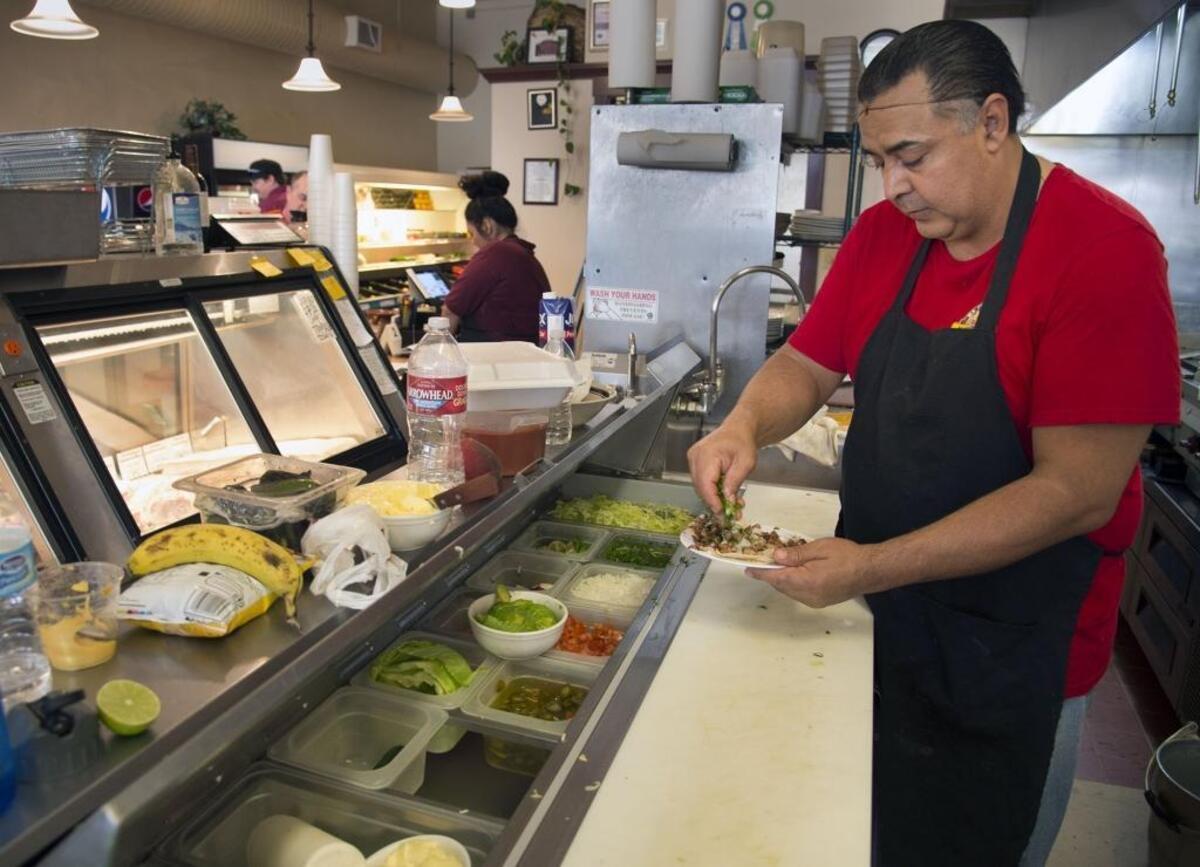 Luis Santana, a cook at the El Pueblo Meat Market & Deli in Winters, makes up an order of chili verde tacos.