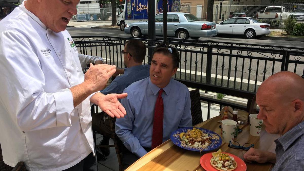Michael Phillips speaks with customers Dave Cloninger and Dough Williams about his inspiration for their fish taco dishes.