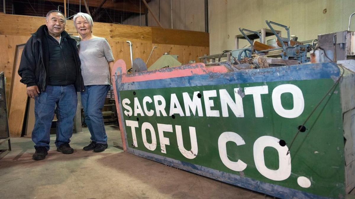 Alvin and Dorothy Kunishi stand next to the sign that once marked the 6th Street location of their Sacramento Tofu Co.