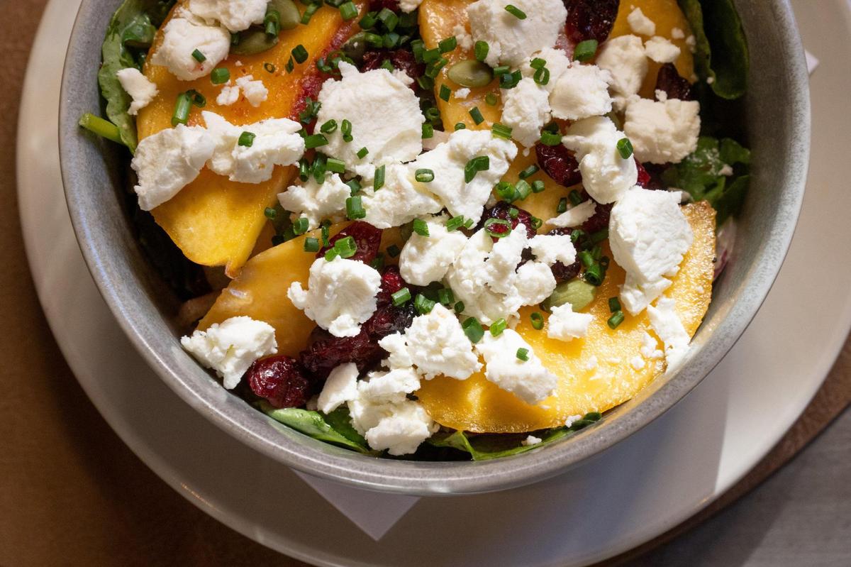 A seasonal peach salad with candied almonds, honey, goat cheese and kale is served at Almighty Food Co. in El Dorado Hills.