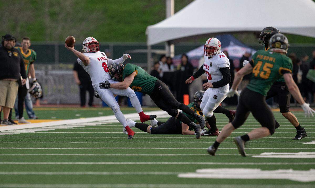 Law Hogs linebacker Travis Stanfield hits Fire Dogs quarterback Cameron Barrios as he releases the ball, forcing a forth quarter interception by defensive end Tim Merrill in the 50th Pig Bowl on Saturday at Hughes Stadium.