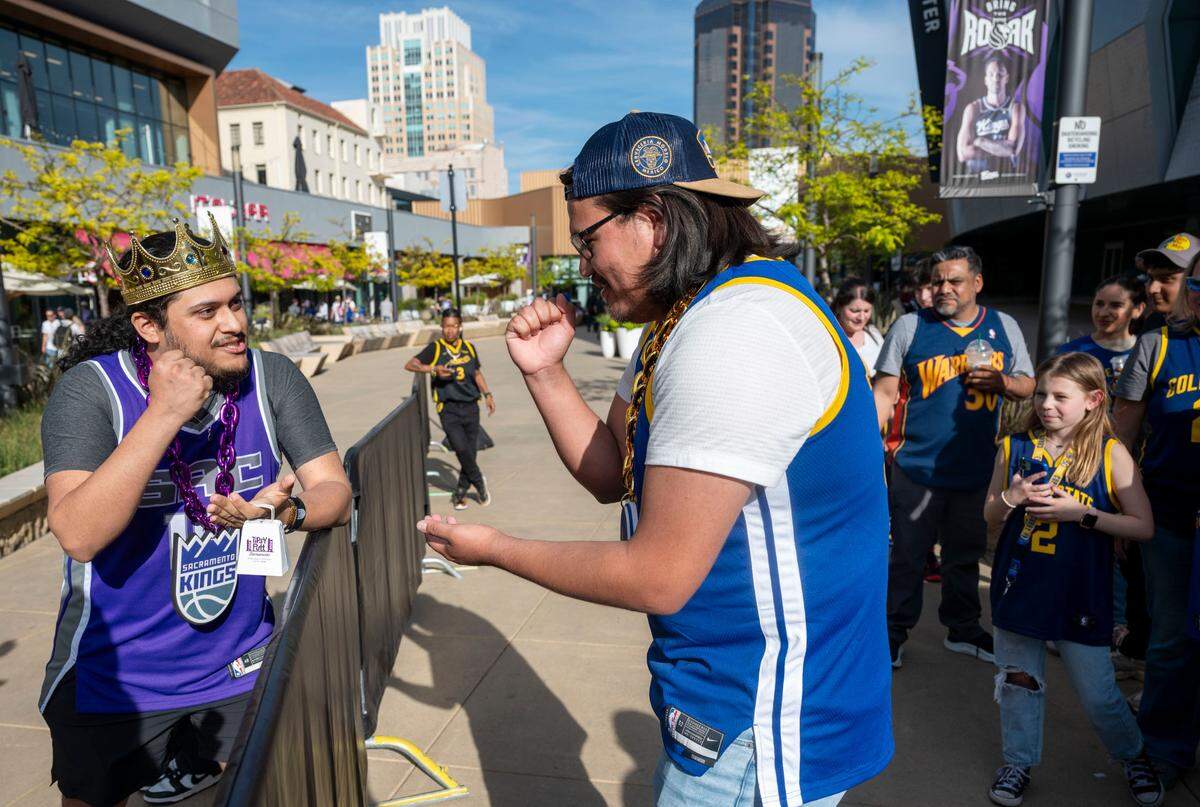Kings fan Luis Hernandez, of Sacramento, and Golden State Warriors fan Manuel Arviso, who just moved from Germany, play a game of rock–paper–scissors while waiting in line to enter the Golden 1 Center before their teams’ play-in game Tuesday.