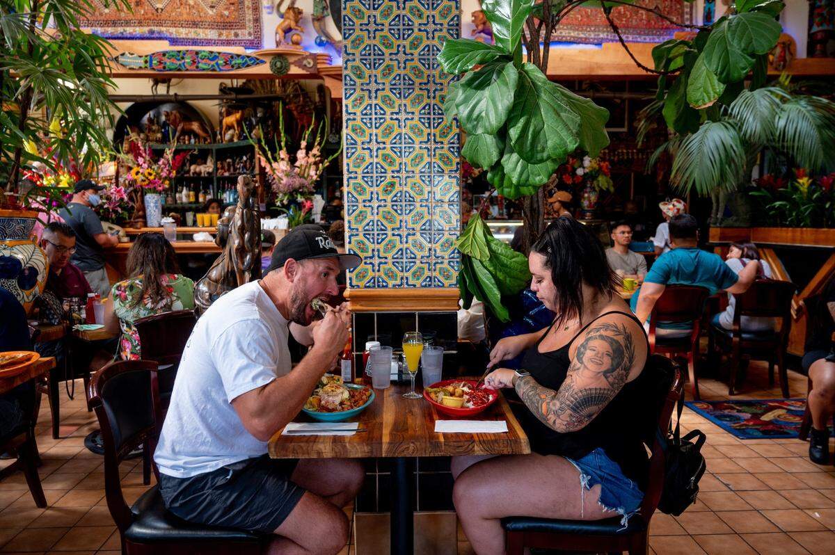 Brett Leach, 38, left, takes a bite of his food as he wife, Meghan Leach, 34, cuts into her meal at Tower Cafe on Sunday, July 18, 2021. After being closed for over a year, this weekend marks the restaurant’s first weekend back serving brunch after coronavirus related closures.