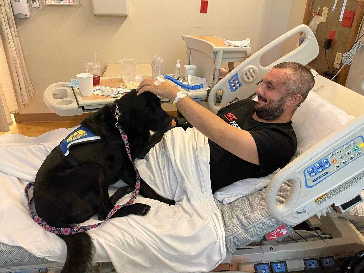 A hospital canine visits Travis Barber, 35, as he recovers at Sutter Rehabilitation Institute in Roseville, California, after suffering brain injuries in an April 2021 shooting.