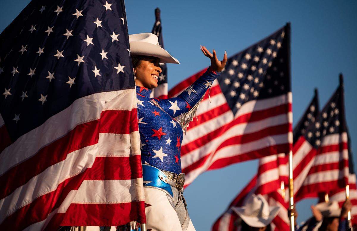 Painted Ladies rodeo performer Jade Sweeney, of Sacramento, stands on a horse named Cody while greeting people arriving to the Star Spangled Drive In Independence Day event, presented by Folsom businesses and organizations in 2020.