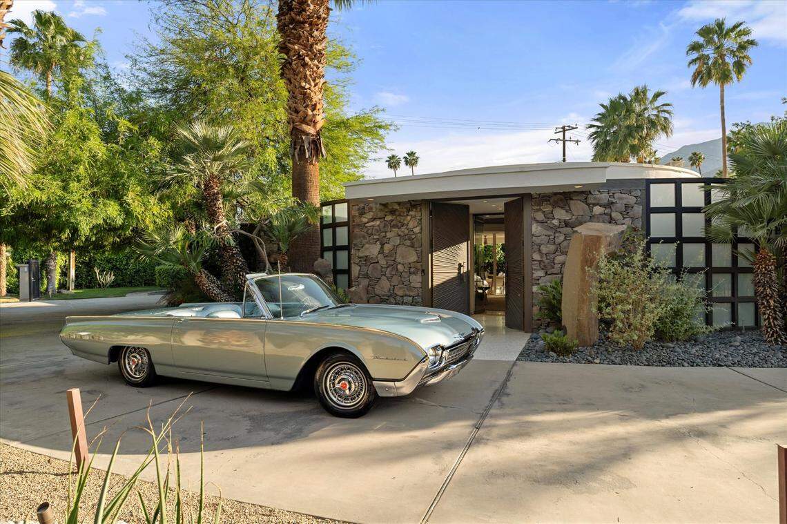 The home’s features include an extraordinary circular living room with 14-foot origami-inspired ceilings, wraparound glass walls, and a suspended fireplace, with views of the San Jacinto Mountains.