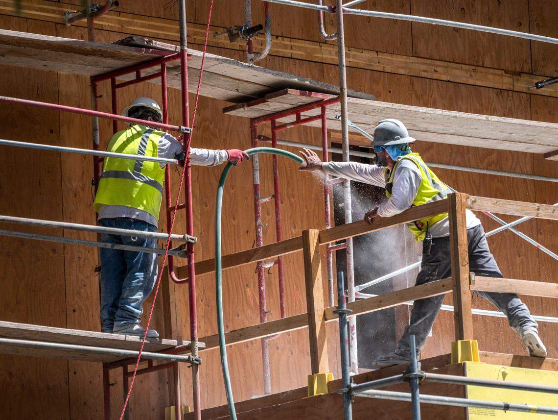 Workers pull a hose at the Sonrisa affordable housing project on Wednesday on O Street in Sacramento. The building occupies an underutilized infill site that is close to public transit, jobs and services.