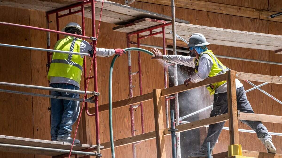 Trabajadores tiran de una manguera en el proyecto de viviendas asequibles Sonrisa, el miércoles 8 de junio de 2022, en O Street en Sacramento. El edificio ocupa un sitio subutilizado cercano al transporte público, los empleos y los servicios.