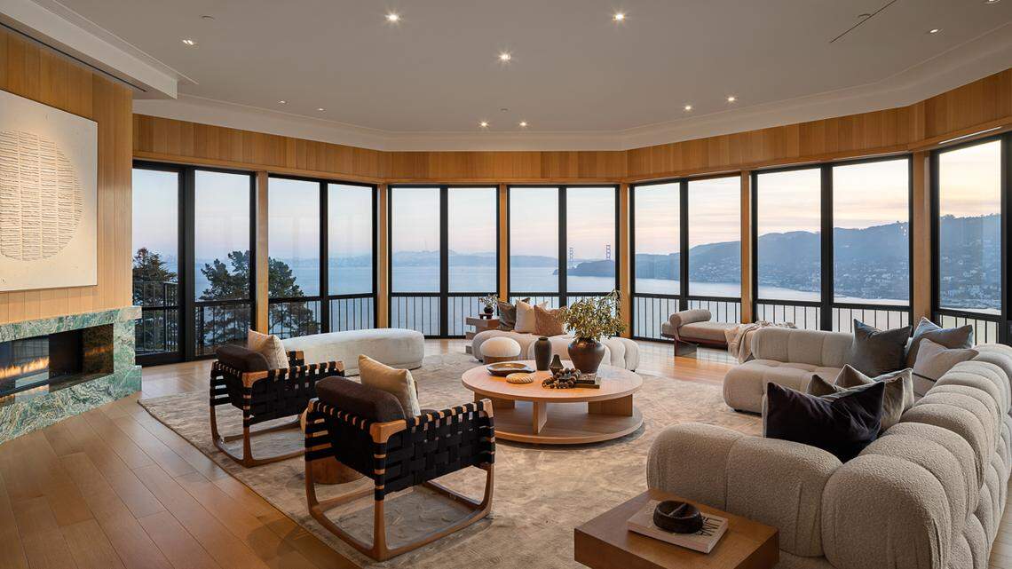 The property at 20 Crest Road in Marin County has a dramatic living room with “curving walls of glass showcasing sweeping views of the San Francisco Bay.”