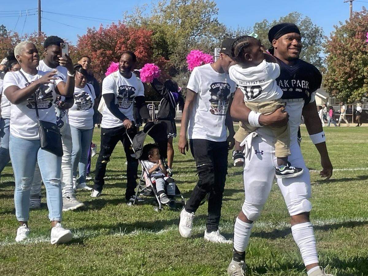 Senior running back Darius Moore walks the field with his family during Sacramento Charter High School’s senior day pregame ceremony on Saturday.