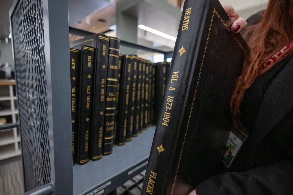 An employee at the Placer County Elections Office holds a volume of historical death records in July that are stored at the facility. The county moved the office from Auburn to a new facility in Rocklin late last year.