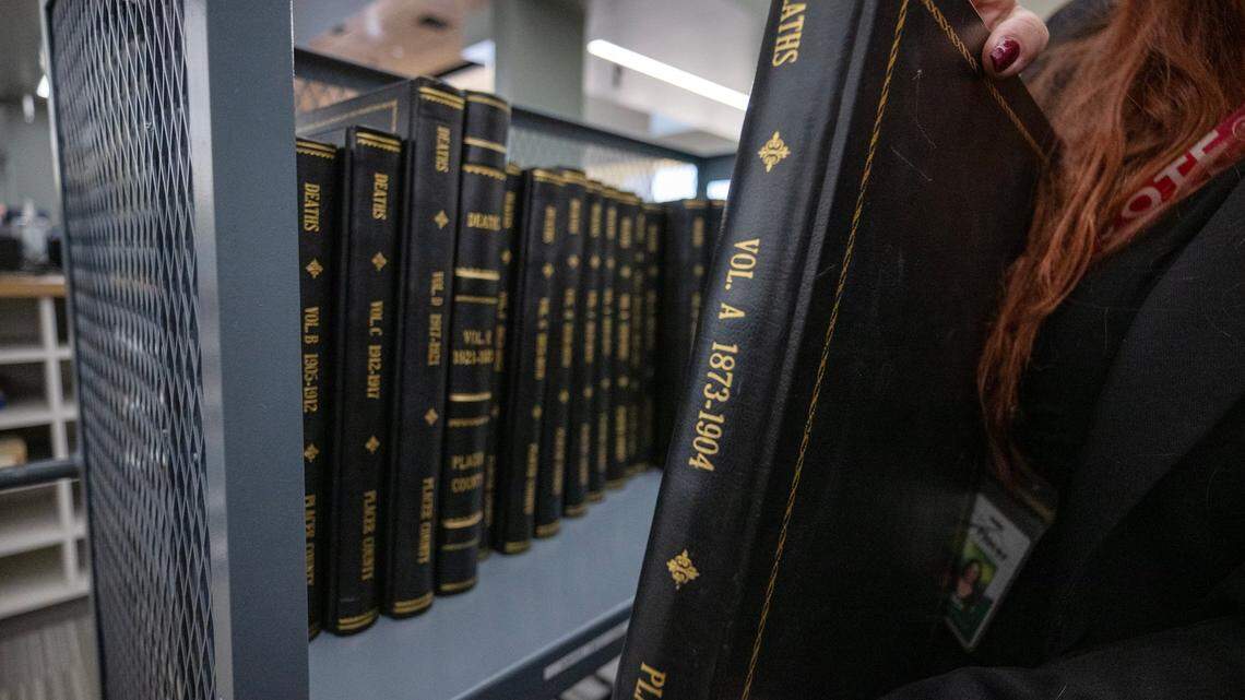 An employee at the Placer County Elections Office holds on July 26, 2024, a volume of historical death records that are stored at the facility. The county moved the office from Auburn to a new facility in Rocklin late last year.

