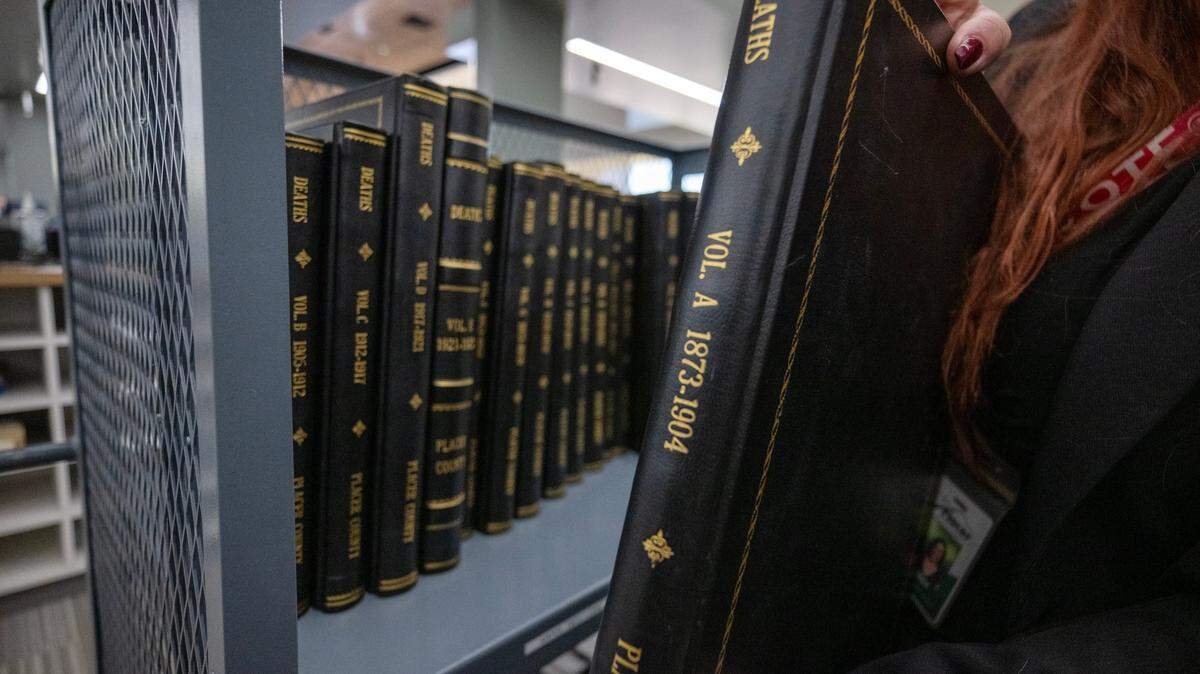 An employee at the Placer County Elections Office holds on July 26, 2024, a volume of historical death records that are stored at the facility. The county moved the office from Auburn to a new facility in Rocklin late last year.

