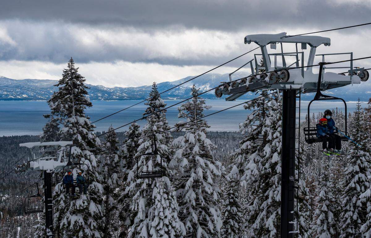 The trees are heavy with snow as skiers ride a lift at Homewood Mountain Resort above Lake Tahoe on Jan. 4, 2023.