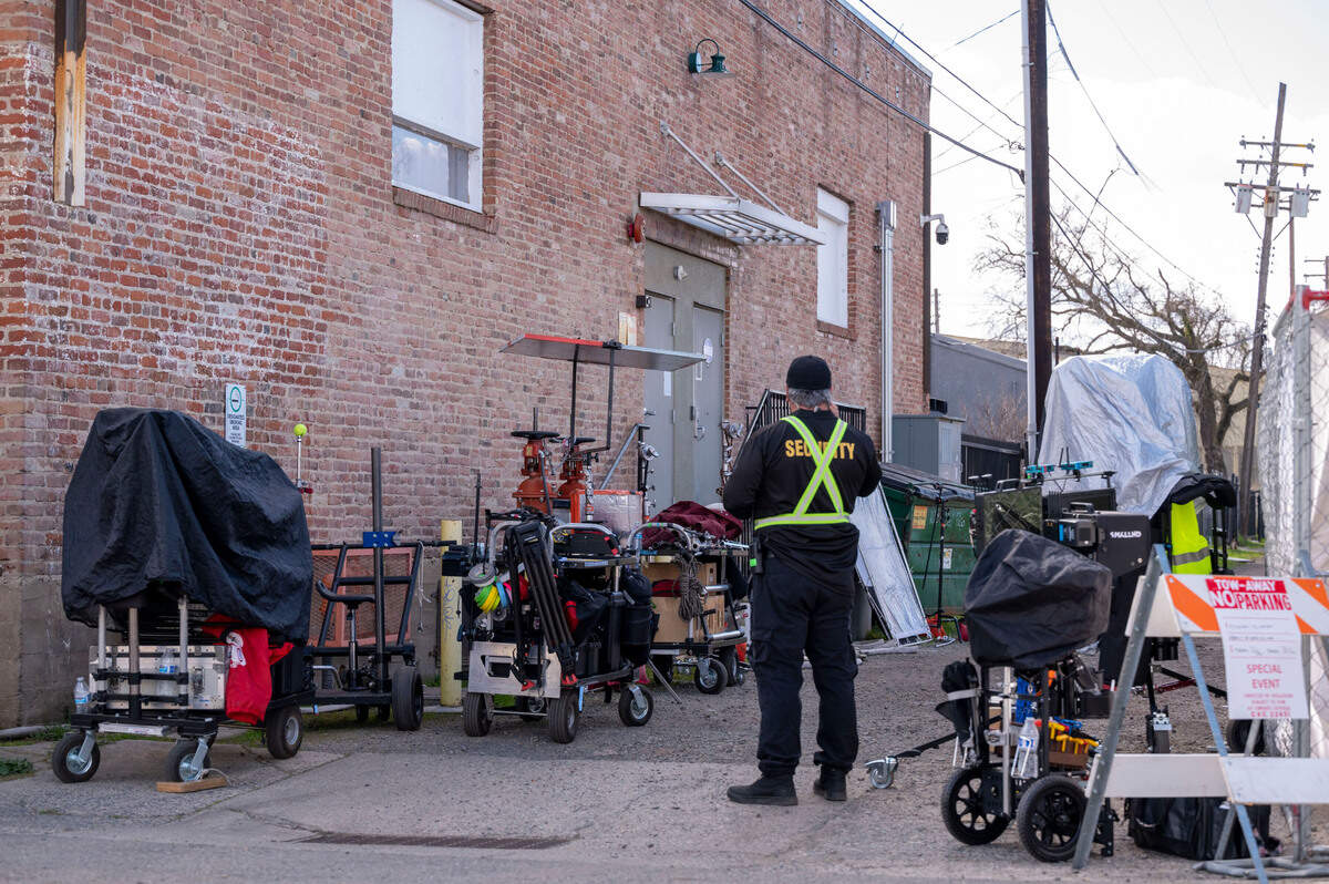 A security guard stands in an alley with filiming equipment where the movie “No Address” is being filmed Wednesday in North Sacramento.