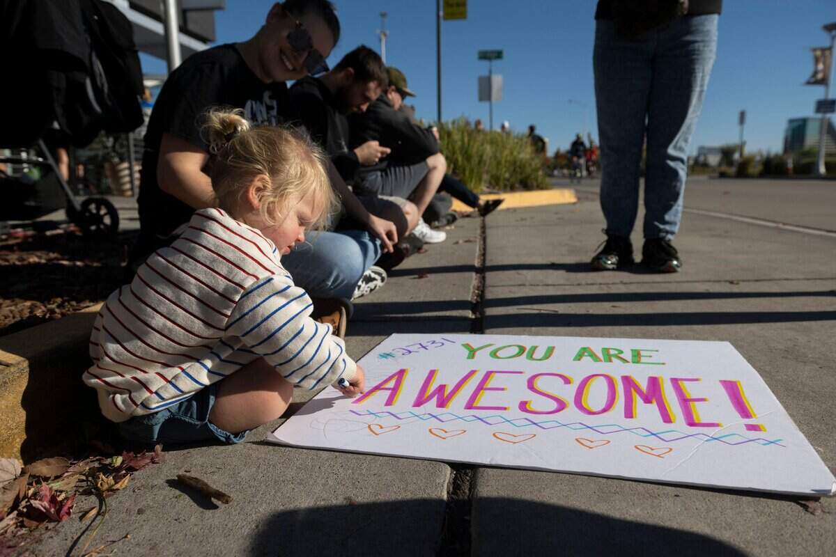 Finn Latham of Oakland draws on a poster for his father Ben, a competitor in the Ironman California triathlon, in Sacramento on Sunday, Oct. 23, 2022.