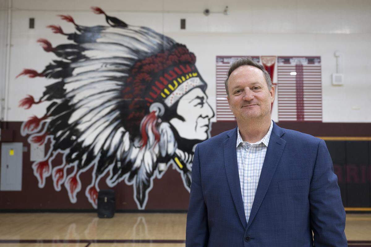 Hiram Johnson High School Principal Garrett Kirkland poses for a portrait in front of a controversial mural in the school’s gym in Sacramento on Tuesday. A petition circulating to remove the mural and the name has received over 300 signatures.