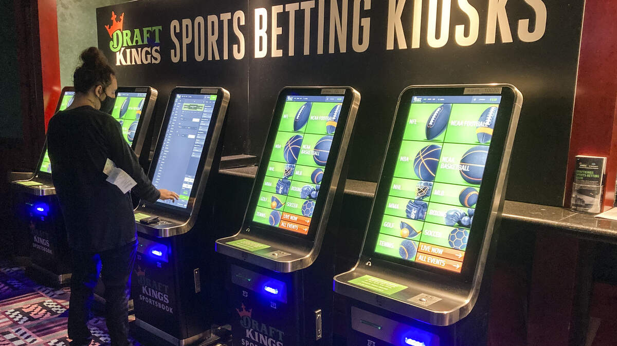 FILE - In this Thursday Sept. 30, 2021, file photo Zach Young, of New Haven, Conn., places a bet at one of the new sports wagering kiosks at Foxwoods Resort Casino in Mashantucket, Conn. Thousands of virtual bets started being placed early Tuesday, Oct. 19, 2021, the first day that online sports wagering and casino games were made available to all eligible adults within Connecticut. (AP Photo/Susan Haigh, File)