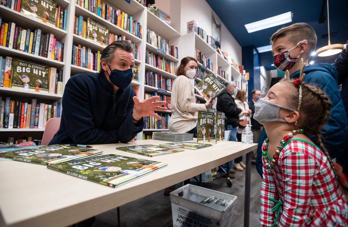 Ellie Gooch, 5, laughs while talking with Gov. Gavin Newsom after he signs a copy of his children’s book, “Ben and Emma’s Big Hit,” for her at Capital Books on Saturday, Dec. 11, 2021, in downtown Sacramento. Newsom said he wrote the book, based on his struggles with dyslexia, to help inspire kids to see their learning differences as gifts.