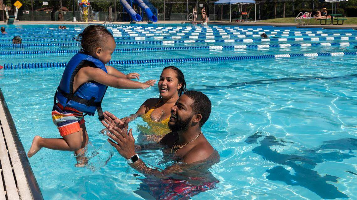 Conrad Hallowell Jr. jumps in the arms of parents Conrad and Lashelle Hollowell at Clunie Pool in Sacramento on Friday, June 18, 2021, as the temperature reached 110 degrees in the city.