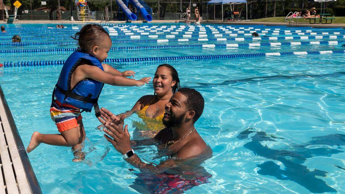 Conrad Hallowell Jr. jumps in the arms of parents Conrad and Lashelle Hollowell at Clunie Pool in Sacramento on Friday, June 18, 2021, as the temperature reached 110 degrees in the city.