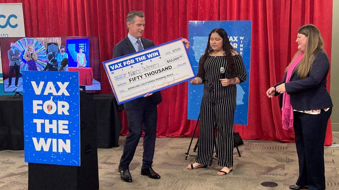 Gov. Gavin Newsom presents a check to Nancy Gutierrez, the winner of $50K lottery for getting vaccinated as Assemblywoman Tasha Boerner Horvath, right looks on in San Diego, Calif. on Friday, June 11, 2021. (AP Photo/Elliot Spagat)